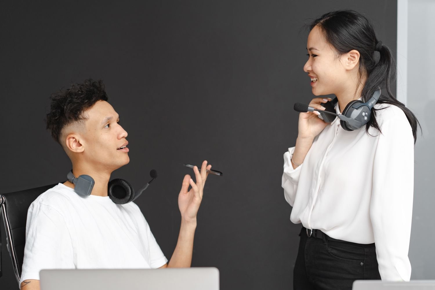 Two colleagues with headsets talking at a desk