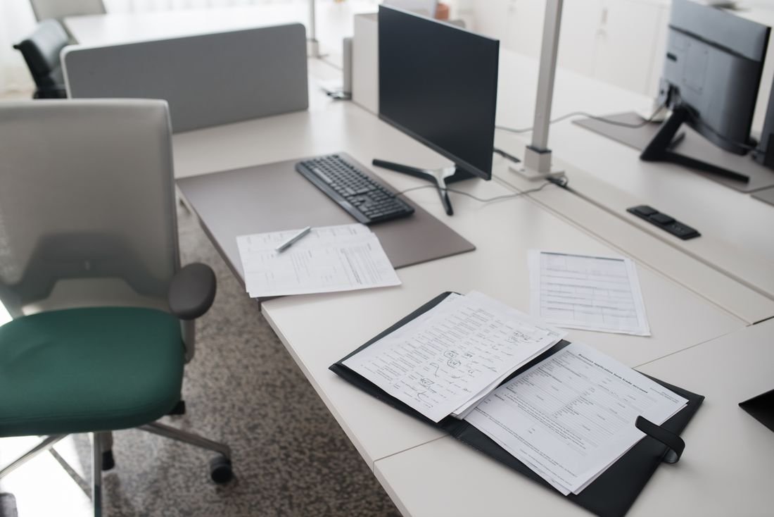 Office desk with forms in a binder beside a computer